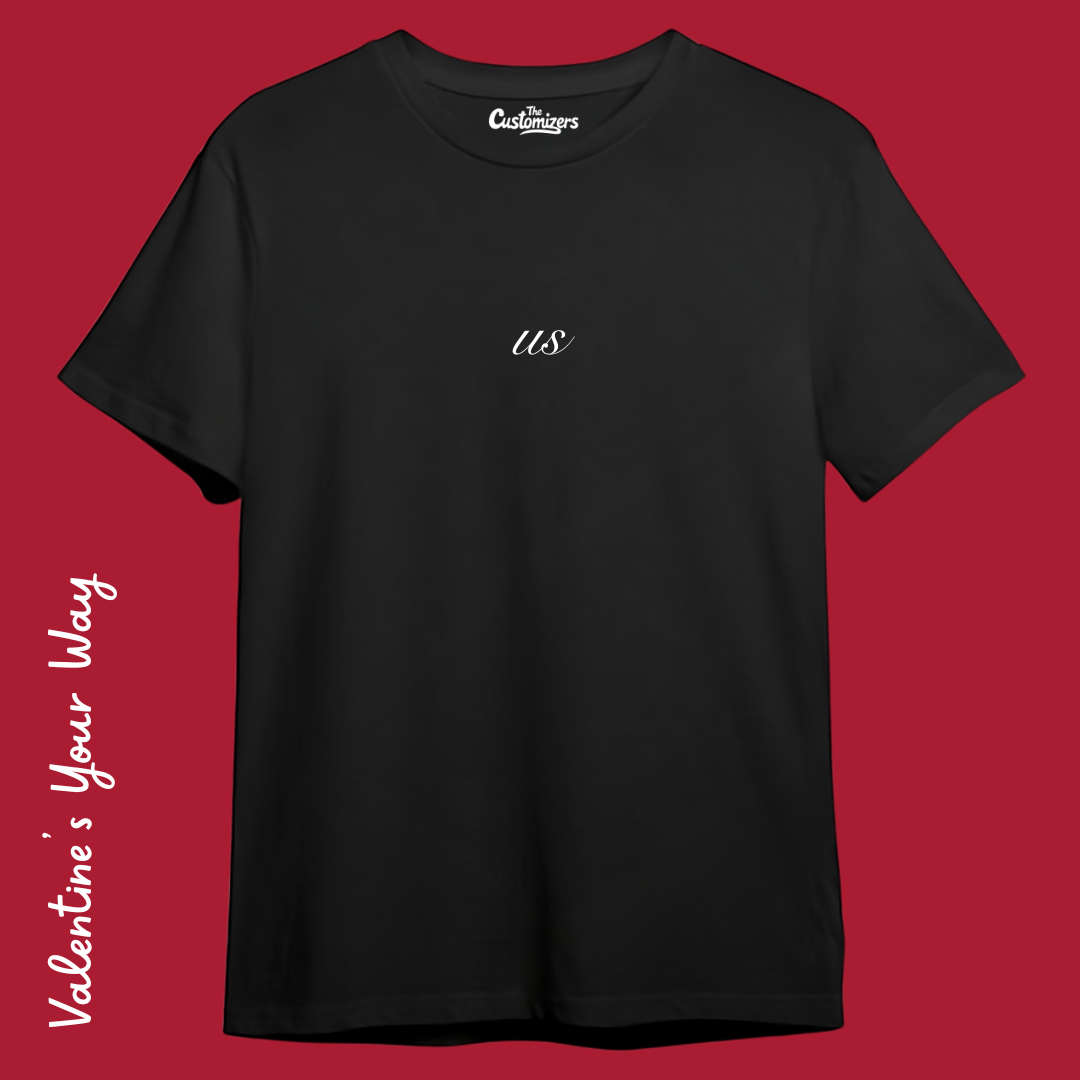 Front view of a custom black t-shirt by The Customizers with a small, white "us" script centered on the chest.